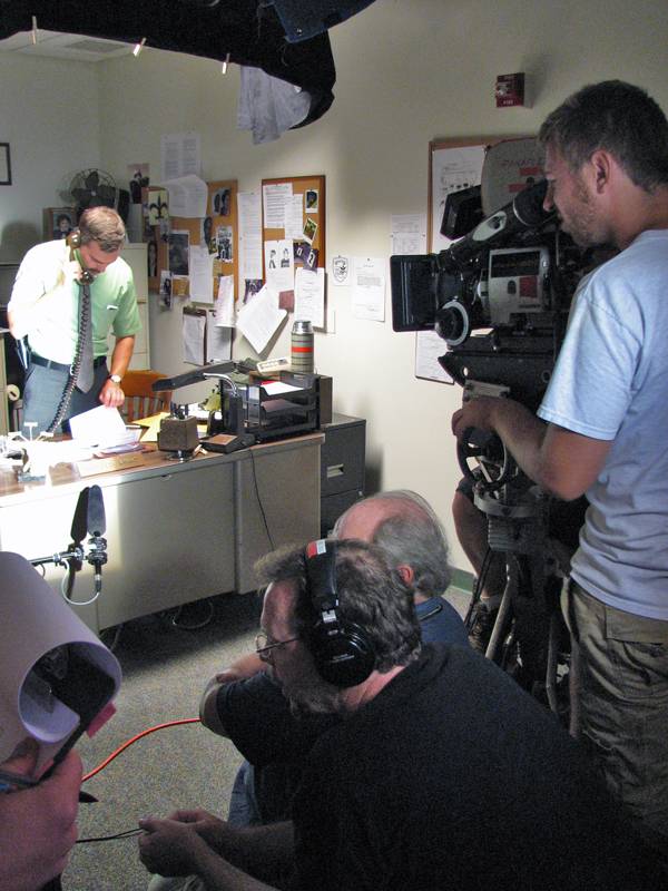 The summer film crew pointing a camera at an actor in a fake office